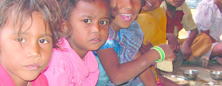 Indische Kinder, die am Boden sitzen und essen